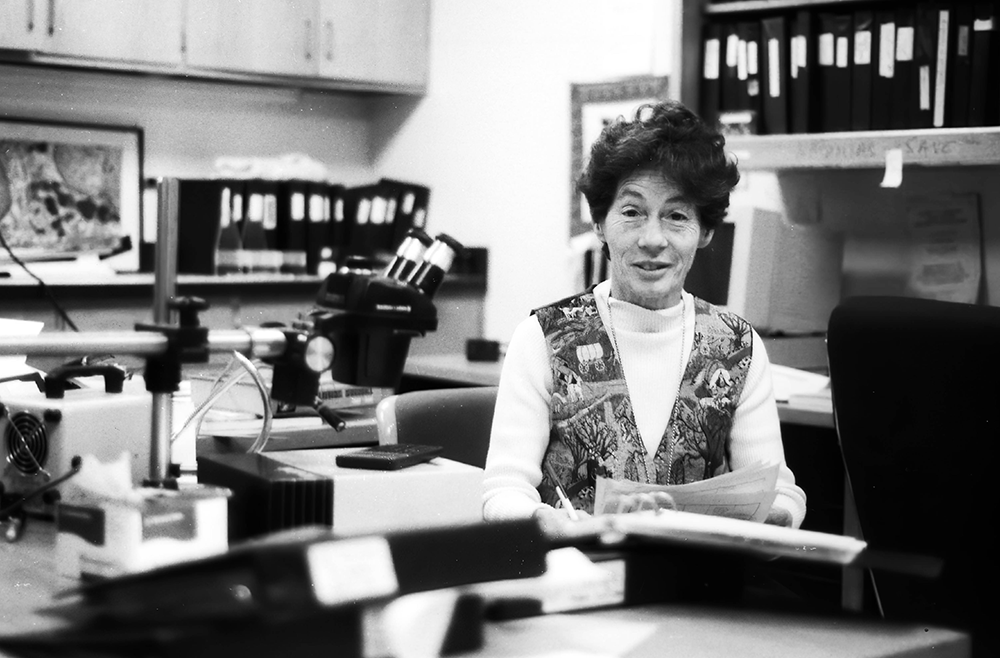  Clara Franzini-Armstrong surrounded by ring binder volumes that hold prints of electron micrographs